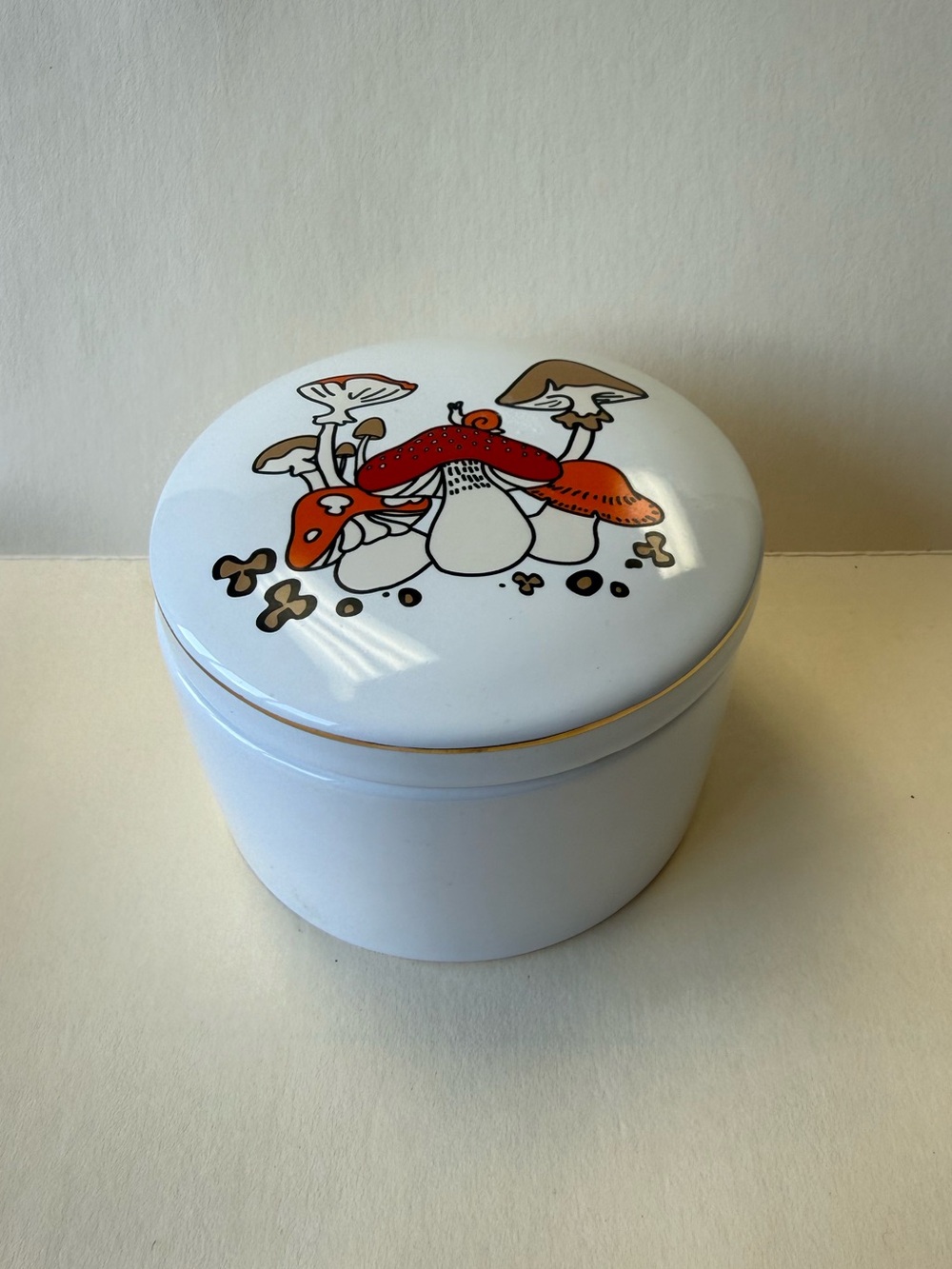 White Round Ceramic Mushroom and Snail Trinket Box with Red and Orange Accents.